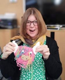 Service user Linzi holding a highland cow she made from cardboard and wool